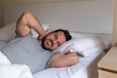 Man waking up with neck pain caused by poor pillow support during sleep
